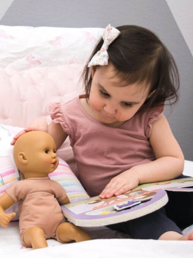 toddler reading book to baby doll