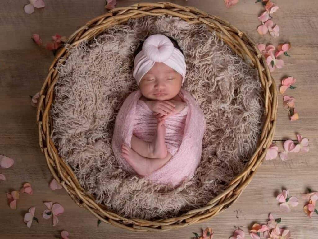 baby girl charlotte in a basket with flower petals around